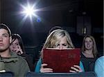 Girl reading hardcover book at movie theater