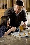 Girl in kitchen with man baking cookies