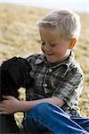 Boy sitting on grass outdoors with puppy