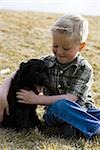 Boy sitting on grass outdoors with puppy