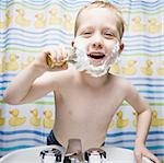 Boy shaving in bathroom and smiling