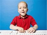 Boy sitting at keyboard smiling