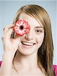 Close-up of woman smiling holding flower up to her eye