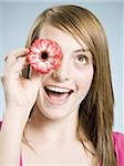 Close-up of woman smiling holding flower up to her eye