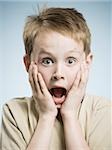 Boy with hands on face and mouth open surprised