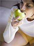 Woman sitting and eating green apple