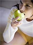 Woman sitting and eating green apple