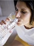 Femme assise et boire de l'eau en bouteille