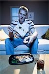 Man on sofa with frozen dinner and napkin with food