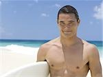 Homme avec planche de surf sur la plage souriant