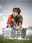 Smiling boy hugging and bathing dog outdoors on cloudy day