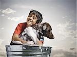 Smiling boy hugging and bathing dog outdoors on cloudy day