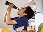 Boy drinking chocolate syrup from bottle in refrigerator