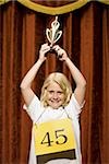 Girl contestant holding trophy and smiling