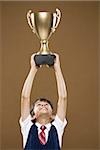 Boy holding Trophäe Pokal über Kopf lächelnd