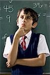 Boy at chalkboard with math formulas thinking