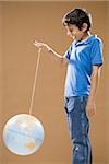 Boy holding string with globe attached smiling