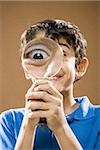 Boy holding magnifying glass to face smiling