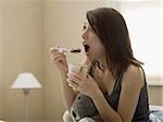 Femme manger la crème glacée au chocolat au lit avec animal en peluche