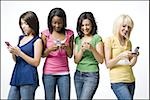 Quatre femmes avec les téléphones cellulaires souriant