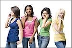 Four women talking on cell phones smiling