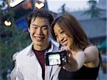 Couple embracing and smiling outdoors with camera