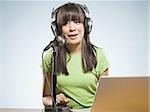 Woman with headphones and laptop singing into microphone