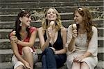 Trois femmes assis sur les marches manger à l'extérieur des cornets de crème glacée souriant