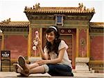 Teenage girl sitting outdoors with cell phone