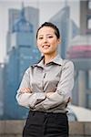 Businesswoman smiling outdoors with arms crossed