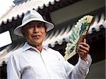 Mature man holding fan and smiling with motion blur