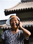 Woman with sun visor outdoors smiling talking on cell phone