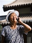 Femme avec pare-soleil extérieur souriant talking sur téléphone portable