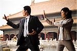 Businesswoman and man doing tai chi outdoors