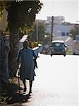 Rear view of woman with cane and head scarf walking down street