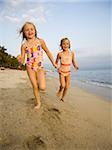 Young girls running in the surf.