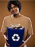 young man in a brown shirt holding a recycling bin.