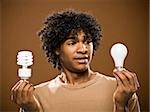 young man in a brown shirt holding light bulbs.