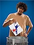 young man in a brown shirt throwing away a political party symbol.