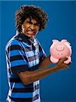 young man trying to get money out of a piggy bank.