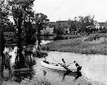 1940s 1950s PAIR OF BOYS IN ROWBOAT WITH COLLIE FISHING IN FARM AREA