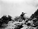 1940s US ARMY INFANTRY MEN SHOOTING RIFLES IN ACTION CARRYING HEAVY BACKPACKS DURING WW2 COMBAT