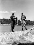 1930s 2 MEN FISHERMAN FISHING HOLDING UP DAYS CATCH TROUT LAKE OF THE WOODS ONTARIO CANADA ADVENTURE MALE BONDING