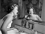 FEMME SOURIANTE DES ANNÉES 1950 ONT ACCÈS À UNE SALLE DE BAIN MIROIR BROSSAGE DES DENTS