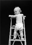 1940s REAR VIEW OF BABY CLIMBING LADDER TURNING HEAD BACK TOWARD CAMERA