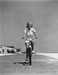 1940s BLOND WOMAN RIDING BIKE ON BEACH BOARDWALK SUMMER