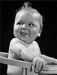 1940s BABY IN HIGH CHAIR HEAD TURNED TO ONE SIDE WITH TONGUE STICKING OUT SILLY HAPPY FUNNY EXPRESSION