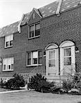 1950s TWO FRONT DOORS OF ATTACHED BRICK ROW HOUSES WITH FRONT STOOP STAIRS