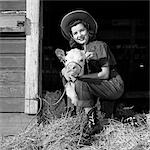 GIRL POSING WITH CALF IN STRAW FILLED STALL IN BARN
