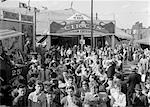 1940s CROWD OF PEOPLE MEN WOMEN OUTSIDE THE ENTRANCE TO A CIRCUS TENT MIDWAY ENTERTAINMENT FUN AMUSEMENT BIG TOP